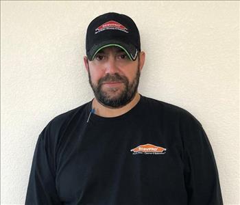 Male employee wearing a hat standing in front of a white background