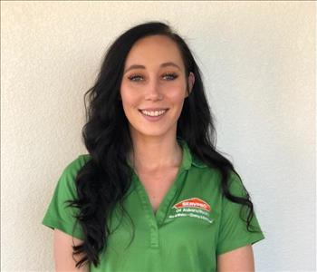 Female employee with black long hair smiling in front of a white background