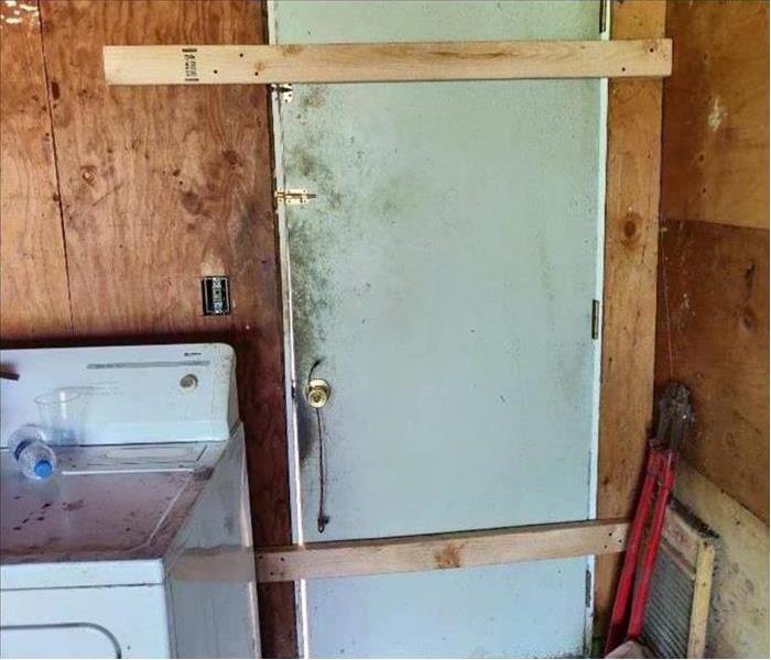 Garage door boarded up with wood securing the side entry to the home